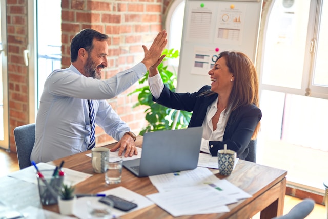 Two business owners high fiving to their success