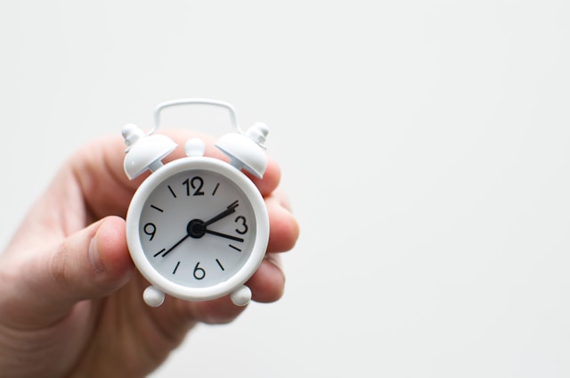 A person holding a little clock