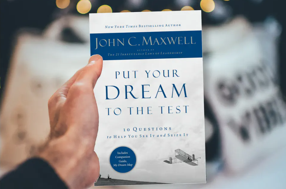 A person holding Put Your Dream to the Test by John C. Maxwell