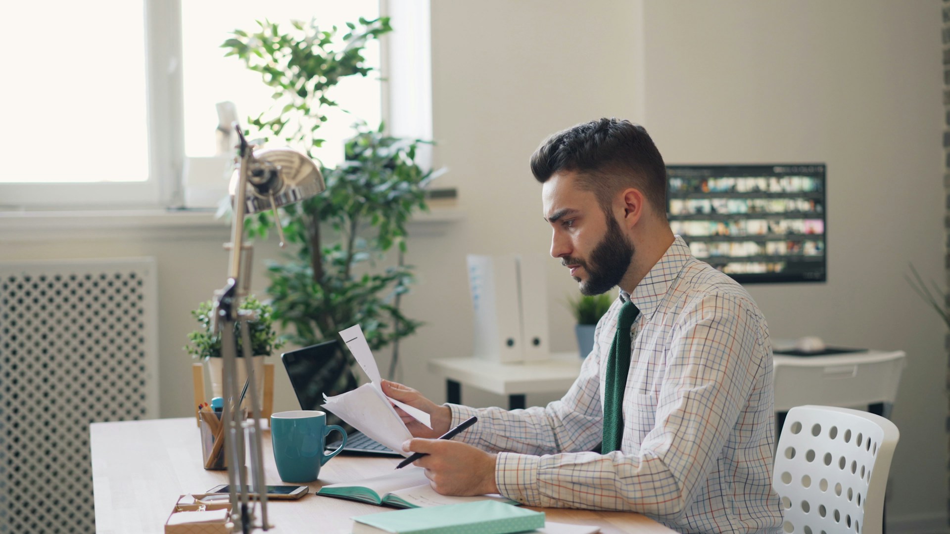 Businessman holding papers and working on his laptop