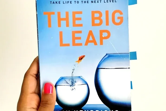 A person holding The Big Leap by Gay Hendricks book