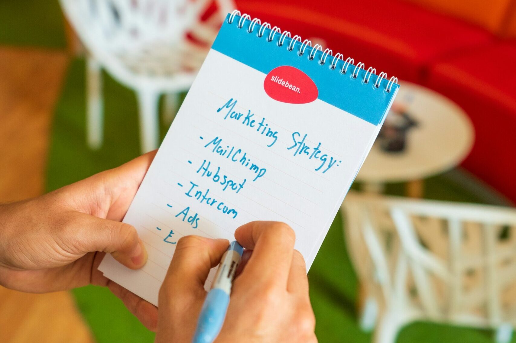 A person holding a marketing strategy written on a notebook