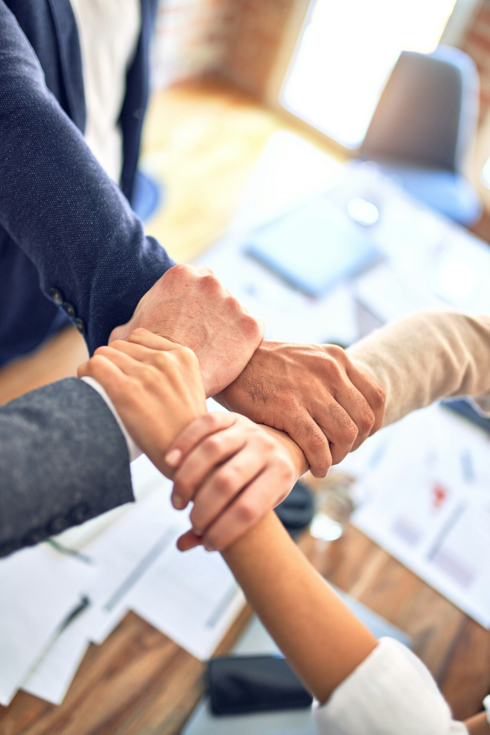 Four corporate employees holding hands in a sign of teamwork