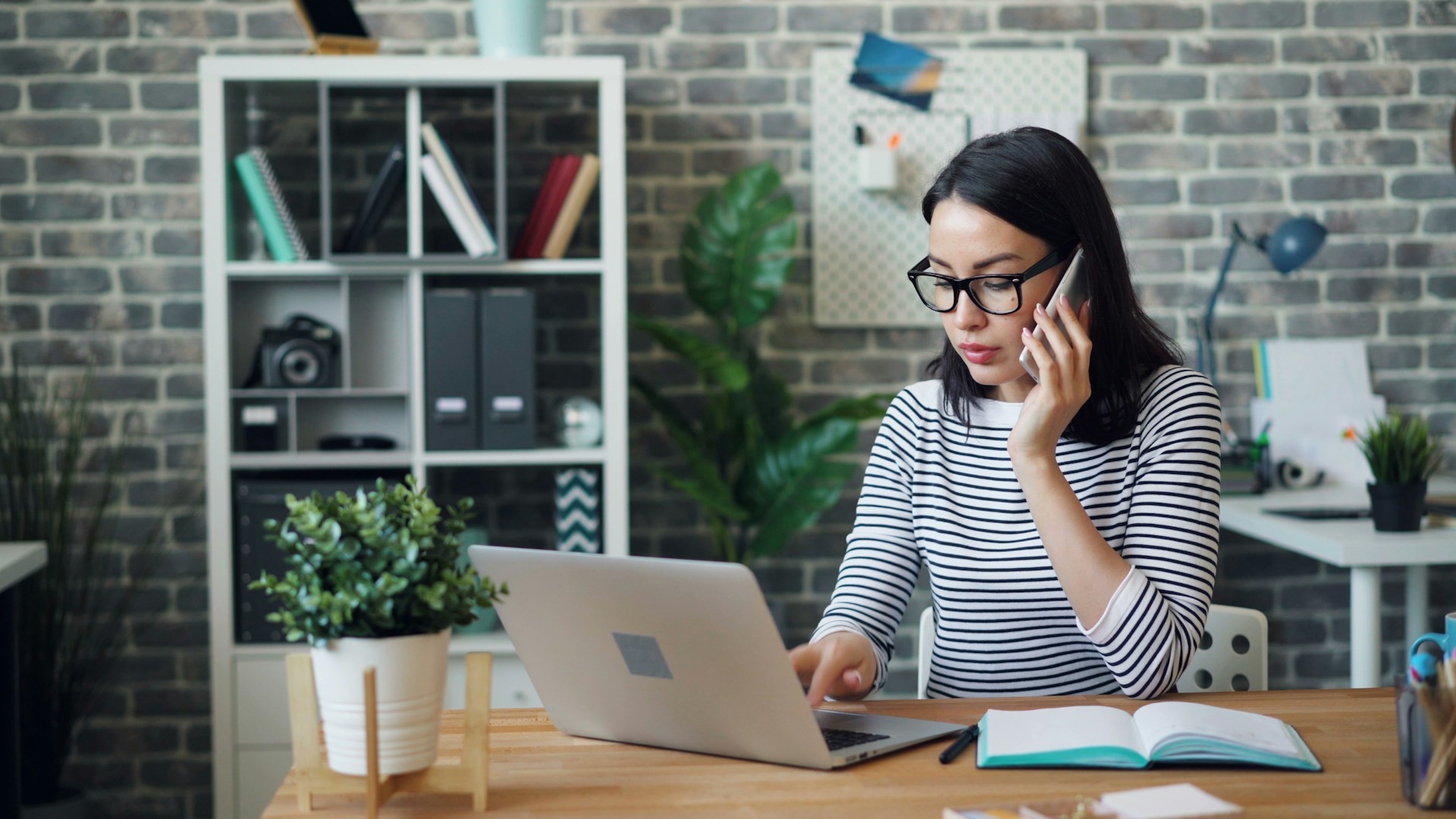 A manager looking at her laptop while talking on the phone